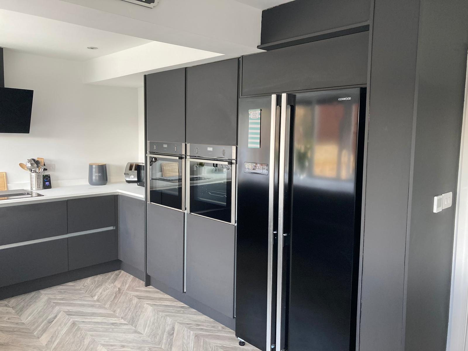 Handleless charcoal kitchen with white worktops and herringbone floor